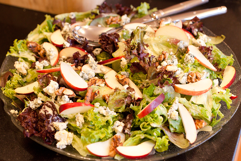 een schaal met sla met stukjes appel en walnoot